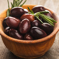 Wooden bowl filled with dark Calamata olives and rosemary on a rustic surface