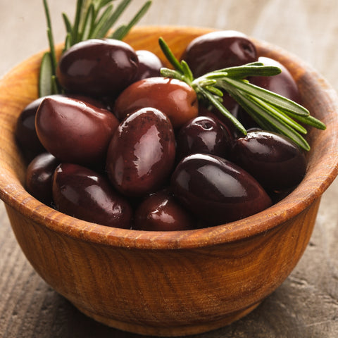 Wooden bowl filled with dark Calamata olives and rosemary on a rustic surface