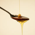 organic agave syrup being poured in a spoon and overflowing