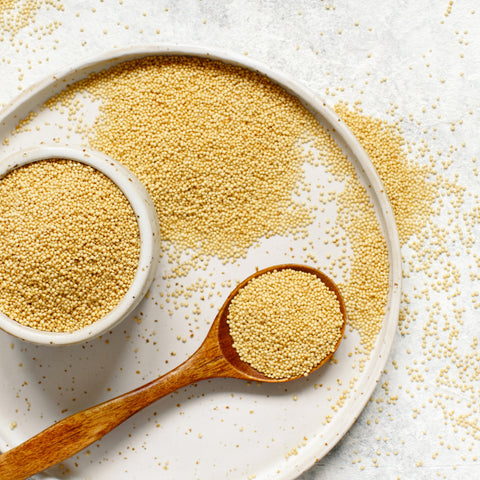organic amaranth grain in bowl and spoon on white table
