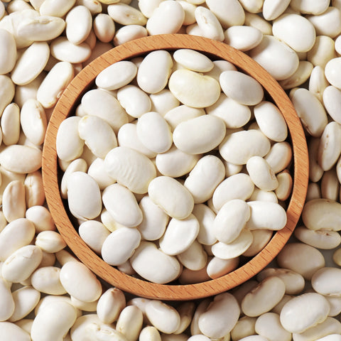 Organic baby lima beans in a wooden bowl surrounded by more beans