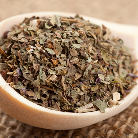 Dried chopped organic basil leaf in a wooden bowl 