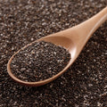 Wooden spoon filled with organic chia seeds on a bed of organic chia seeds.