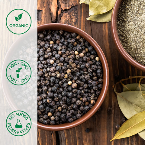 Bowl of organic black peppercorns on a wooden surface 