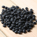 Pile of organic black beans on a wooden surface