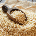 Wooden scoop filled with organic brown basmati rice on a bed of rice