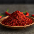 Organic chili powder spice in a wooden bowl on a dark background