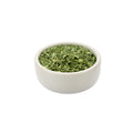 Small white bowl filled with dried organic cilantro on a white background