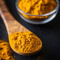Organic ground turmeric on a wooden spoon