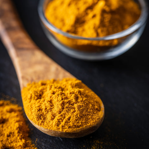 Organic ground turmeric on a wooden spoon