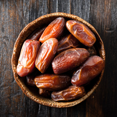 Bowl of organic honey dates on white background