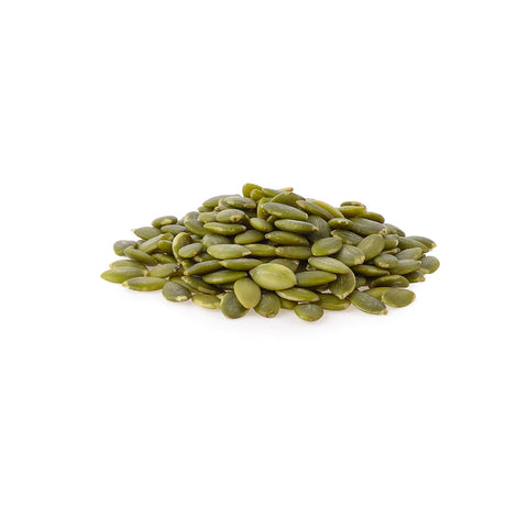 Raw organic hulled pumpkin seeds on a white background