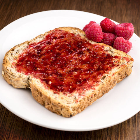 Organic raspberry fruit spread on a piece of bread