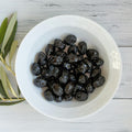 White bowl filled with organic sun dried black olives