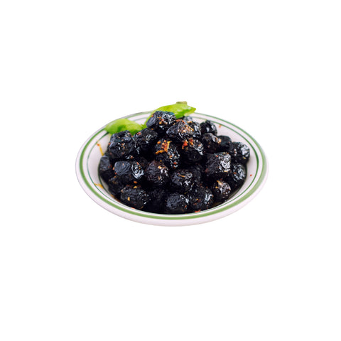 Organic sun-dried black olives with pits on white background 