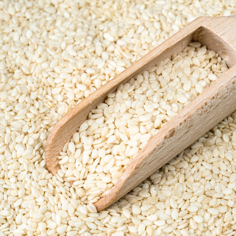 Scoop of organic hulled white sesame seeds