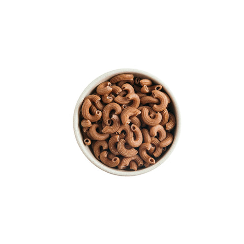 Organic whole wheat elbow macaroni pasta on white background